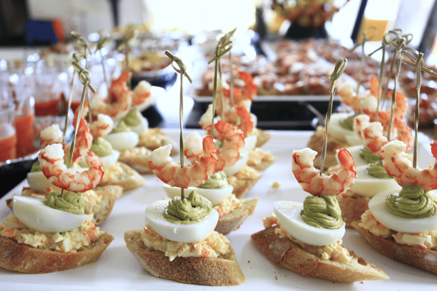 Shrimp appetizers on bread with egg and avocado, arranged on a platter.