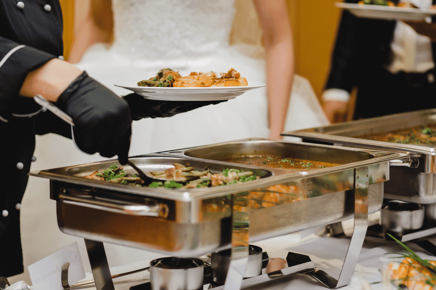 Buffet line at an event with guests selecting dishes from trays.