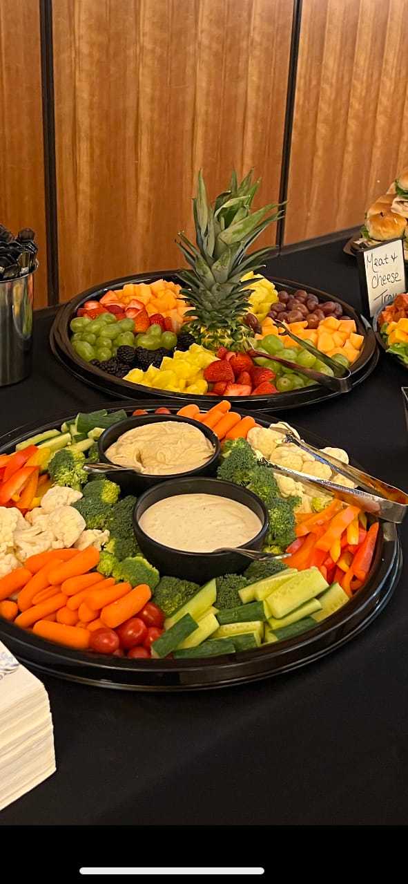 Veggie and fruit trays with dips on a table for an event.