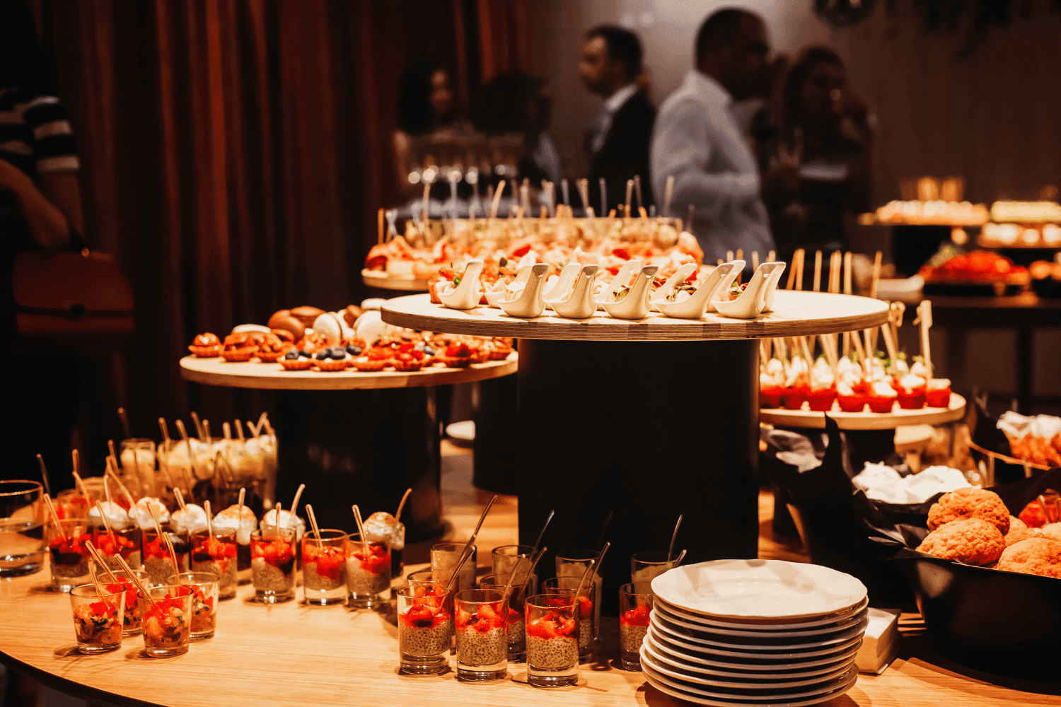 Buffet table with assorted appetizers, including skewers, hors d'oeuvres, and colorful desserts.